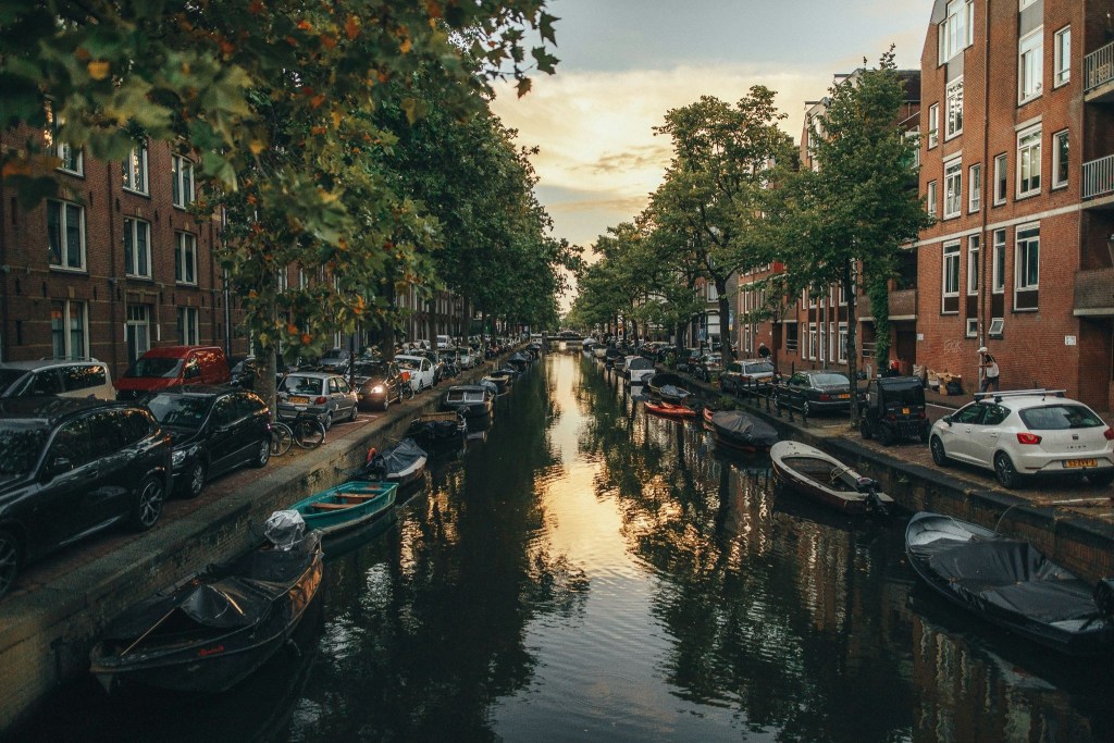 Amsterdam canal with little boats amazing for summer activities and among the best netherlands landmarks.