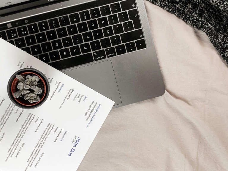 How to write a resume – recruiter reviewing CV on laptop with printed resume