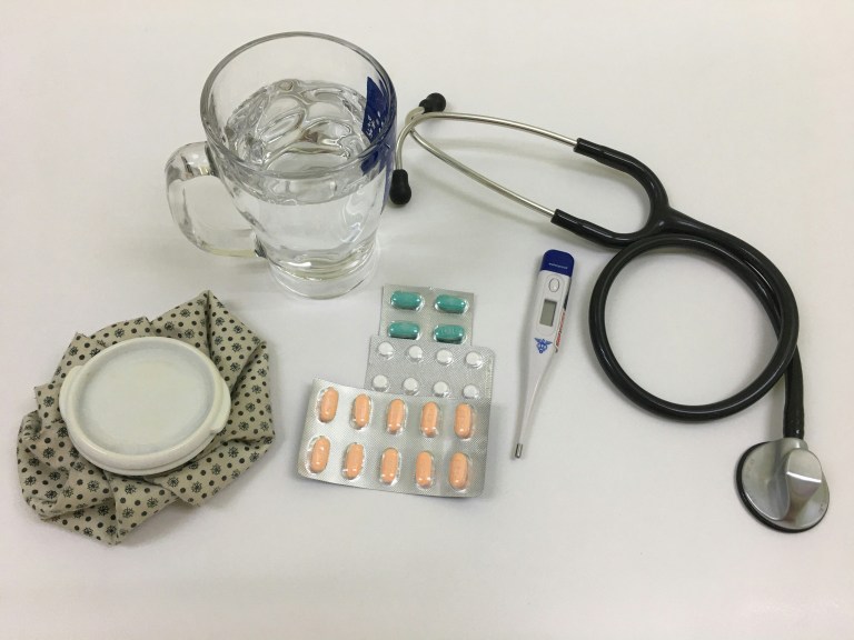 Medicine, water and a stethoscope, representing sick leave and how it is regulated.