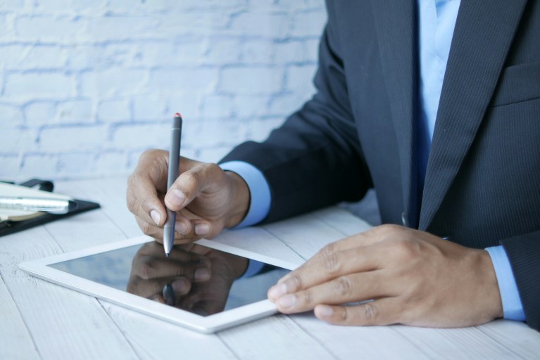 A person signing a document on a tablet, representing different types of employment contracts in the Netherlands, including temporary and permanent contracts.