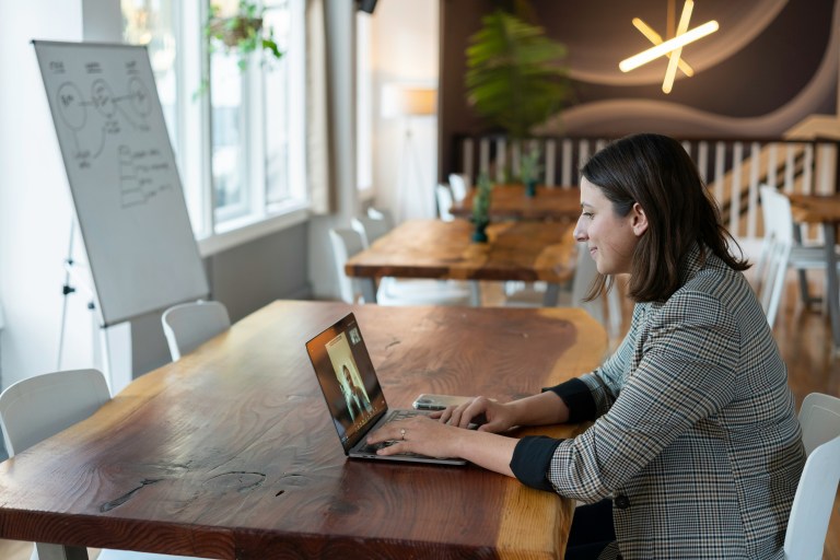 A woman sitting on a desk with her laptop having an online interview.