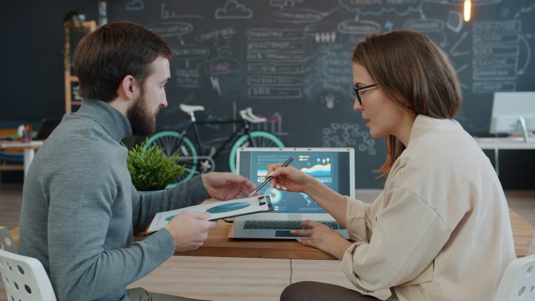 Office team meeting with charts showing employee wellbeing statistics and wellbeing and productivity statistics.