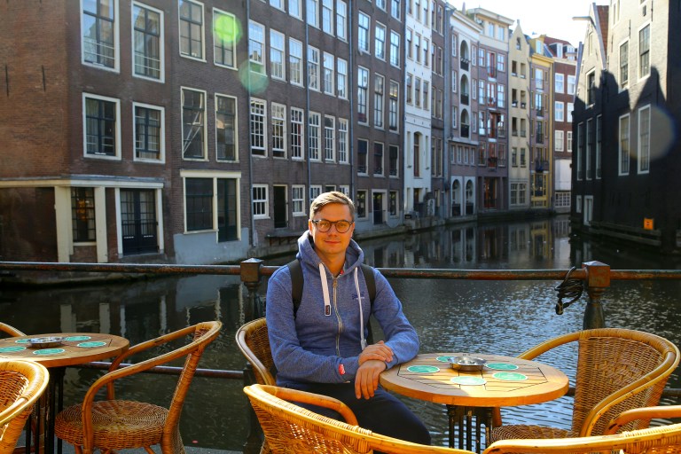 Expat sitting next to an Amsterdam canal representing Dutch citizenship.